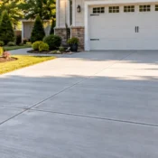 Finished broom-finish concrete driveway with control joints leading to a two-car garage with landscaped beds.